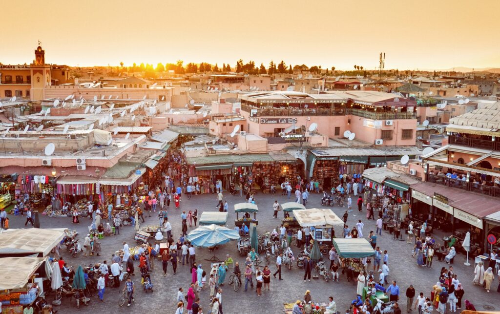 Jemaa el-Fnaa Square in Marrakech in the afternoon with bustling crowds, street performers, and market stalls